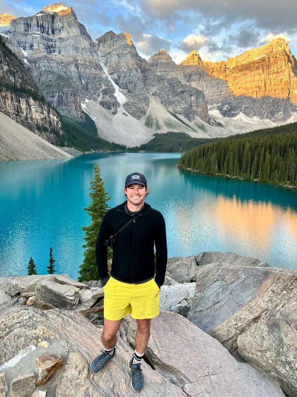 Scott standing on rocks above Moraine Lake, Banff, with the Valley of the Ten Peaks behind him
